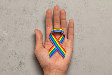 LGBT tape in hand. Pride rainbow ribbon in the hands of a man