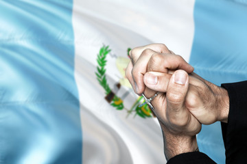 Guatemala flag and praying patriot man with crossed hands. Holding cross, hoping and wishing.