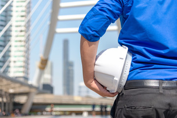 Close up hand architect worker holding white helmet a for workers security control at city site. Engineer inspector construction building in the project site.  Industry and Engineer Concept