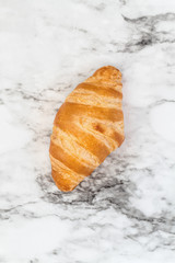 One fresh homemade croissant or crescent rolls over marble background  Image shot from top view. 
