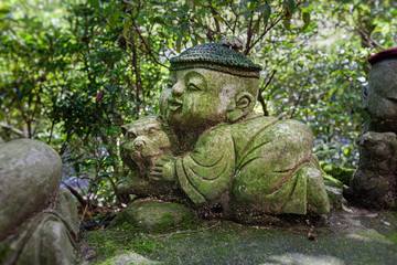 Fototapeta na wymiar Tiger - symbol of japanese horoscope. Childish Jizo stone statue wearing knitted and cloth hats with zodiac animal.