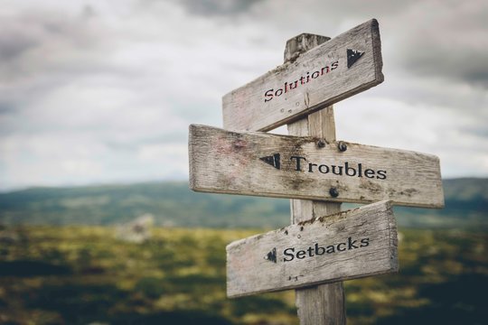 Solutions, troubles and setbacks text on wooden signpost outdoors in nature. Business, corporate, leadership concept.