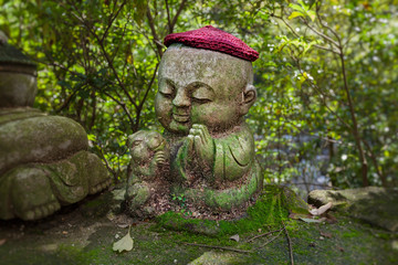 Fototapeta premium Rabbit - symbol of japanese horoscope. Childish Jizo stone statue wearing knitted and cloth hats with zodiac animal.