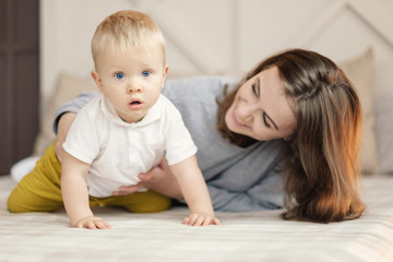 mother teaches the baby to crawl, happy mother and son on the bed
