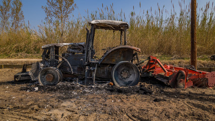 abandoned old burned tractor in field