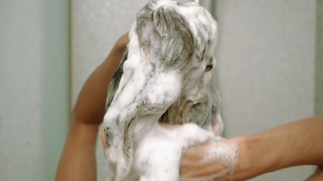 Young attractive woman taking a shower in bathroom. Beautiful girl washing her body under a shower. Slow motion. HD