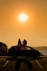 An unidentfied couple eating evening meal on top of a campervan at sunset in Australia.