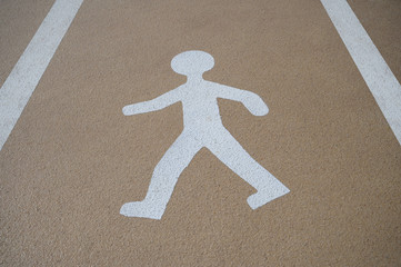 White walking man painted on the ground of a car park.