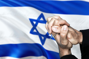 Israel flag and praying patriot man with crossed hands. Holding cross, hoping and wishing.