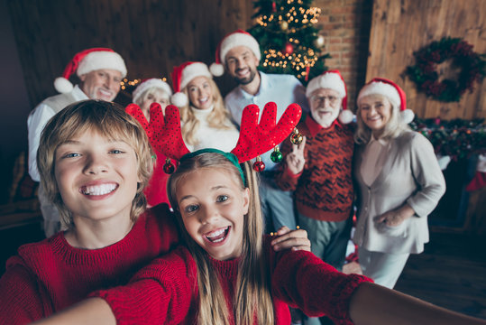Self photo of large family meeting together with couple of brother sister taking selfie on background of their relatives parents grandparents and christmas tree in lights
