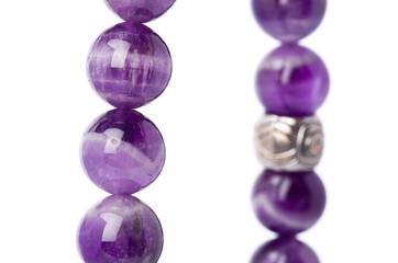 Closeup of a bracelet of amethyst pearls with tibetan metal spacer on a white background