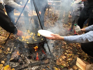 A picnic with a company by the fire. Cooking omelet from eggs on a fire. Chicken eggs on fire in the forest.