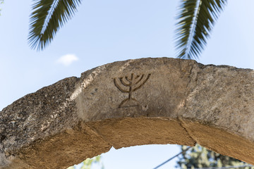 The Israeli symbol - Menorah - carved in stone on an arch at the entrance to the archaeological site of Tel Shilo in Samaria region in Benjamin district, Israel - obrazy, fototapety, plakaty