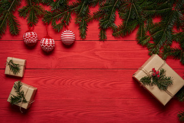 Christmas tree branches with balls and gifts, on red planks