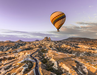 Single tourist hot air balloon floating above the highways of Nevsehir