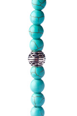 Closeup of a bracelet of turquoise pearls with tibetan metal spacer on a white background