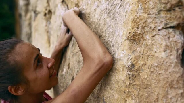 climbing moments. closeup woman's fase and hands reaching and holding rock holds on a yellow cliff. slow motion 120 fps
