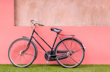 Fototapeta na wymiar Vintage bicycle on lawn and pastel concrete wall background