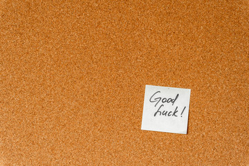 Good luck! Handwritten inspirational supportive lettering on a sticker on a cork board. Background and texture.