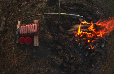 meat and tomato juice over an open fire in the forest late at night at sunset