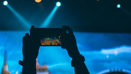 People holding their smart phones and photographing concert . Capture video at a concert at the phone camera in a bright spotlight lamps