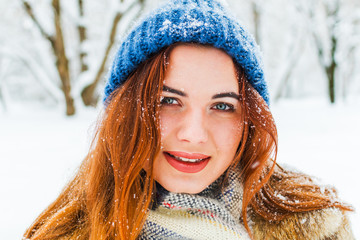 portrait of a beautiful young woman in a scarf and hat. Charming girl in the winter forest. Skin care in winter.