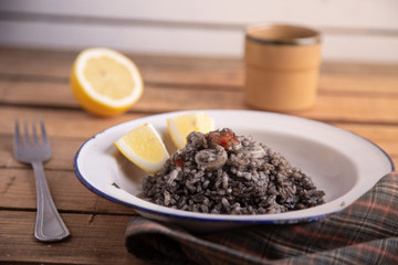 Plate of black rice with squid and prawns or Valencian black paella