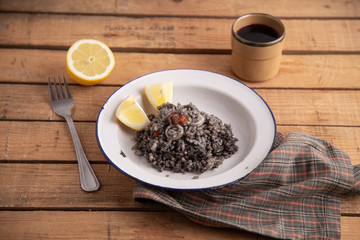 Plate of black rice with squid and prawns or Valencian black paella