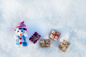 toy snowman with gifts in the snow