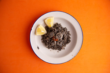 Plate of black rice with squid and prawns or Valencian black paella