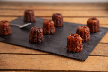 French pastry Caneles de bordeaux rum and vanilla flavor thick caramelized crust on black slate plate..