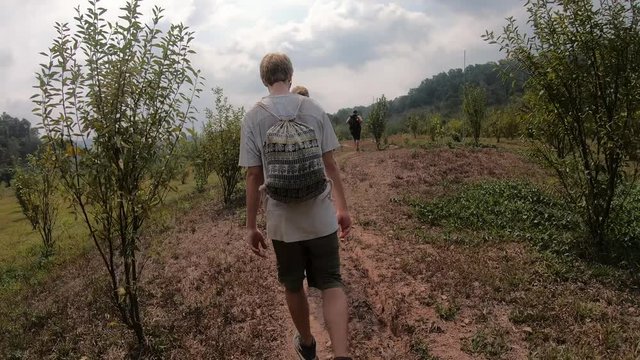 Multiple Young Males Hiking in the Fields of Laos during the Gibbon Experience showing bushes of Fruit