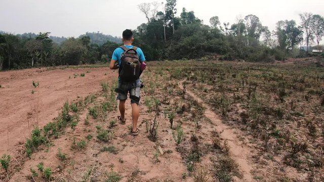 A Guide Walking on a Plain Field during a Gibbon Experience Hike in Laos
