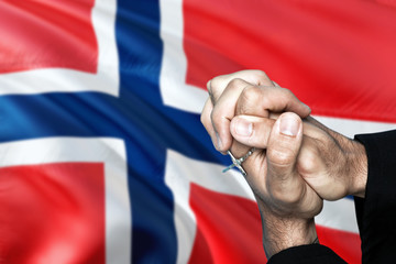 Norway flag and praying patriot man with crossed hands. Holding cross, hoping and wishing.