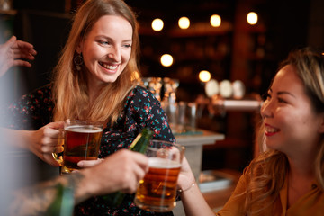 Friends standing in bar and toasting with beer.