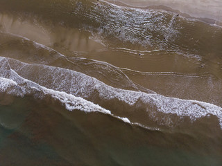 Aerial drone image view of ocean waves crashing on beach 