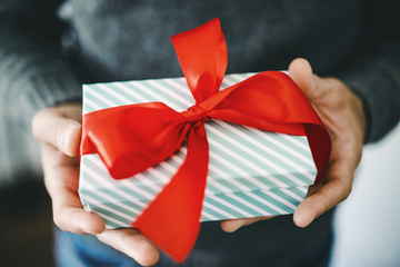 Man holding gift with red ribbon