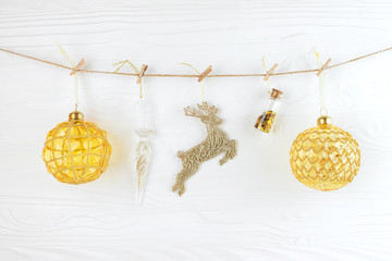 Hanging golden christmas decoration over white wooden background.