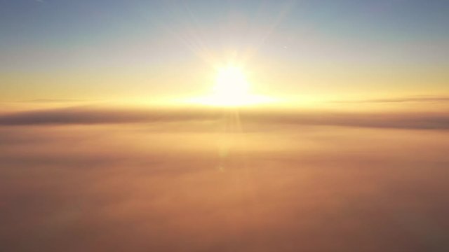 Calm peaceful sunrise just above the misty clouds, meditation, aerial drone view moving towards sun