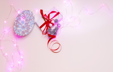 Colorful christmas decoration and gift boxes on the white background in pink light. Xmas or New Year background with place for text.