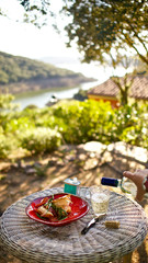 Female hand pouring wine in a glass on a Medditerenean private terrace  with sunny view on the sea
