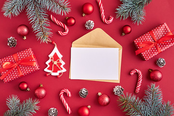 Mockup white greeting card and envelope with red christmas balls, spruce branches and gift box on a red background