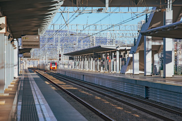 Passenger station with an empty platform without people, a train is visible in the distance.