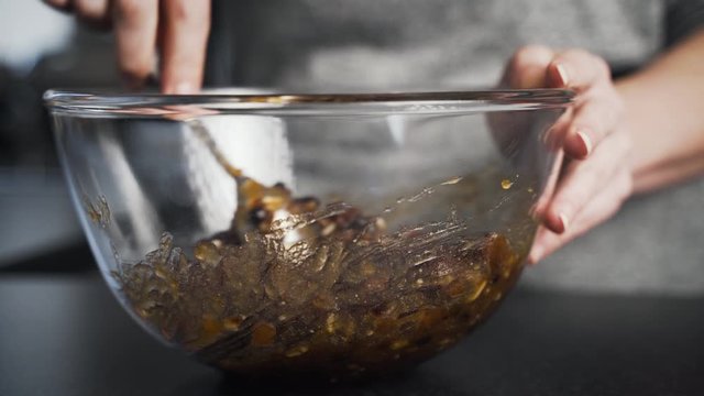 Close up of lady using spoon to stir and mix sticky ingredients in a clear glass bowl to make mince pies for the holidays. Woman cooking in her kitchen baking a seasonal dessert. pastry.