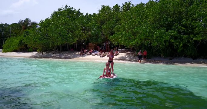 best friends having fun on the paddleboard. Girl rowing in the seawater while her friend is sunbathing