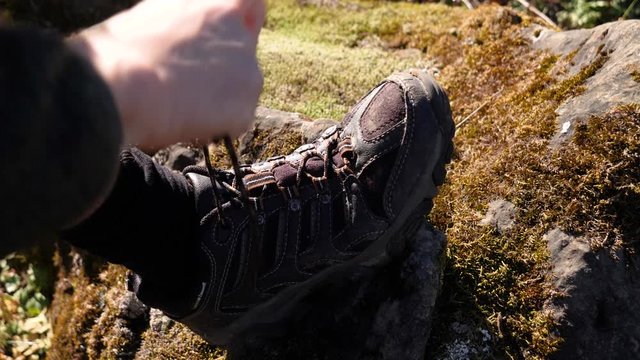 Man's hands tie shoelaces on hiking boots, preparing for hike