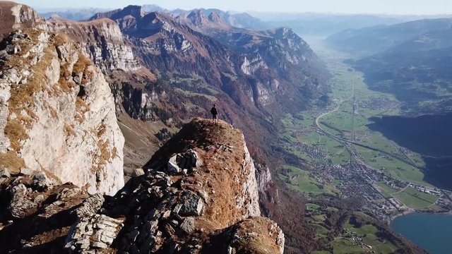 Hiker on edge of cliff on Brisi Mountain in Swiss Alps, epic drone footage