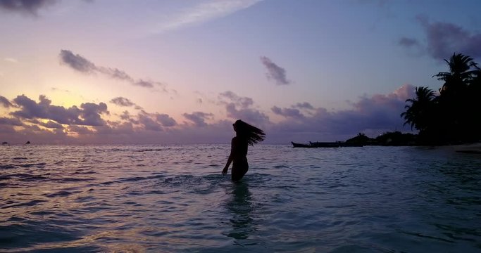 silhouette, young attractive woman enjoying perfect sunset in the water of the tropical island beach