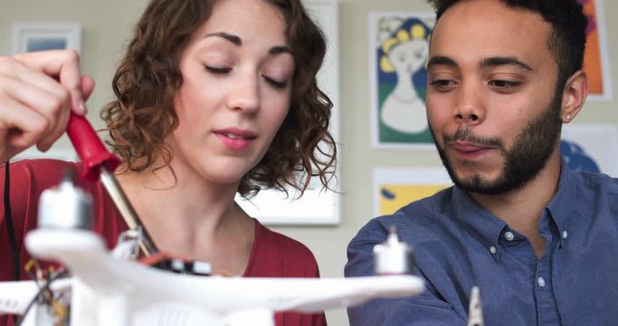 African American Man and Caucasian Woman Working Together To Build A Drone In A Fabrication Fab Lab In Their Startup Business