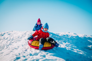 happy cute boy and girl slide in winter snow